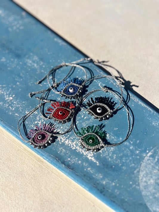 Bracciali Tychi in diversi colori con dettagli argento su fondo bianco e azzurro.
