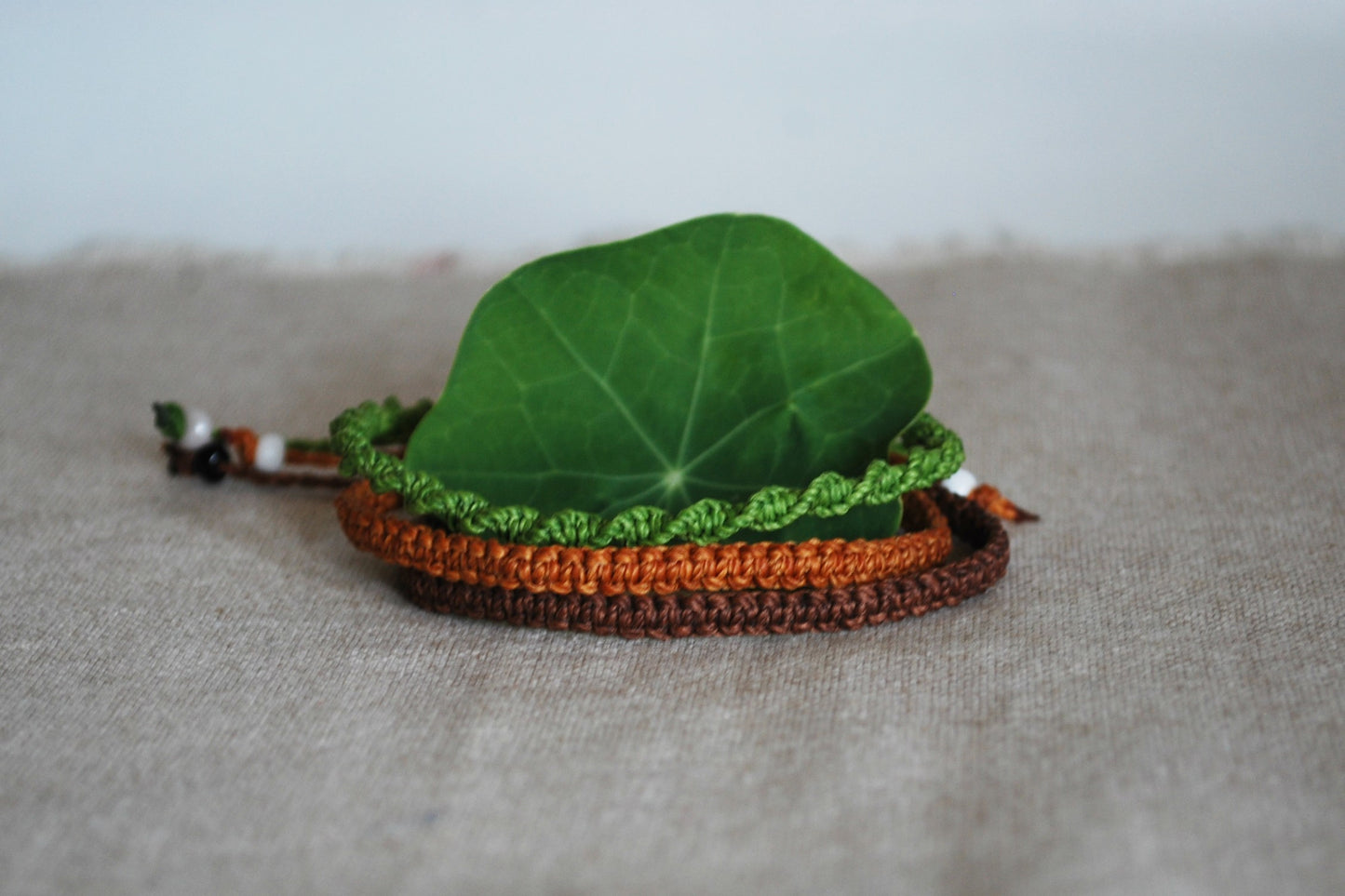 set di tre braccialetti verde lime marrone e terracotta foto con foglia