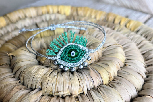 Bracciale Tychi con dettagli argento fotografato su un cestino di paglia